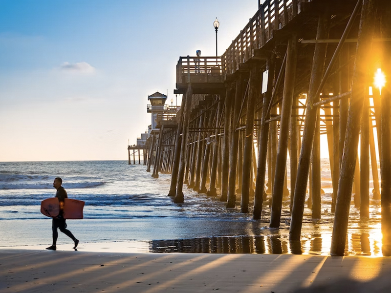 man walking on the beach with his surf board